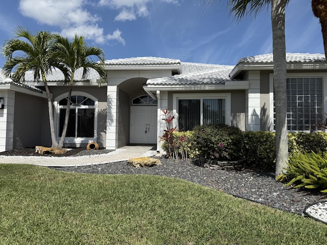 doorway to property featuring a yard, a tiled roof, and stucco siding