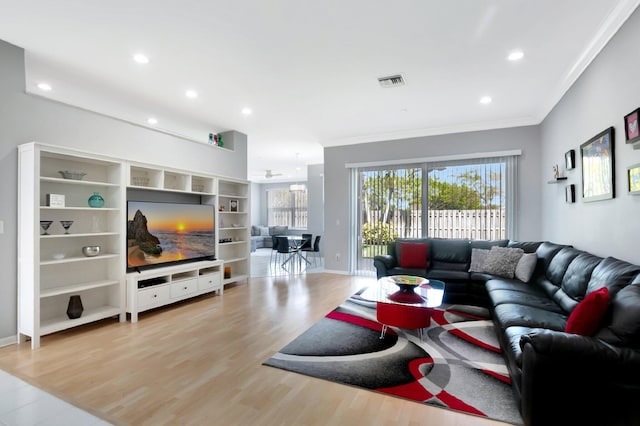 living area featuring light wood finished floors, visible vents, a wealth of natural light, and ornamental molding