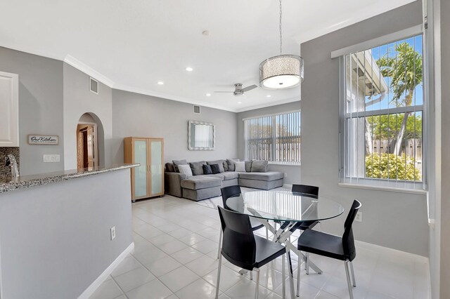 dining area featuring ornamental molding, arched walkways, and a healthy amount of sunlight