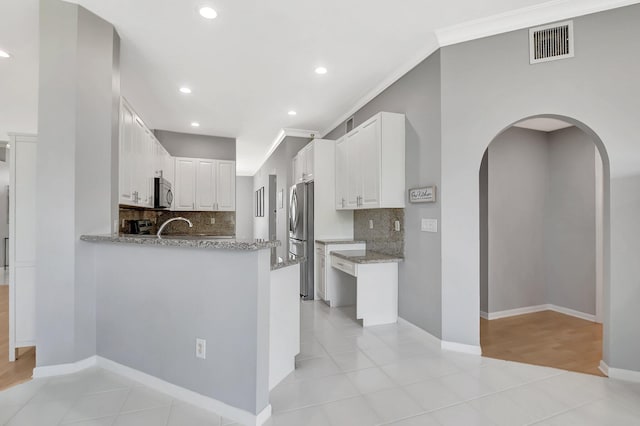 kitchen featuring arched walkways, light tile patterned floors, visible vents, appliances with stainless steel finishes, and crown molding