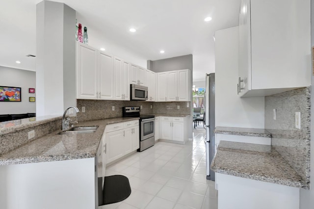 kitchen featuring appliances with stainless steel finishes, a sink, white cabinets, and decorative backsplash