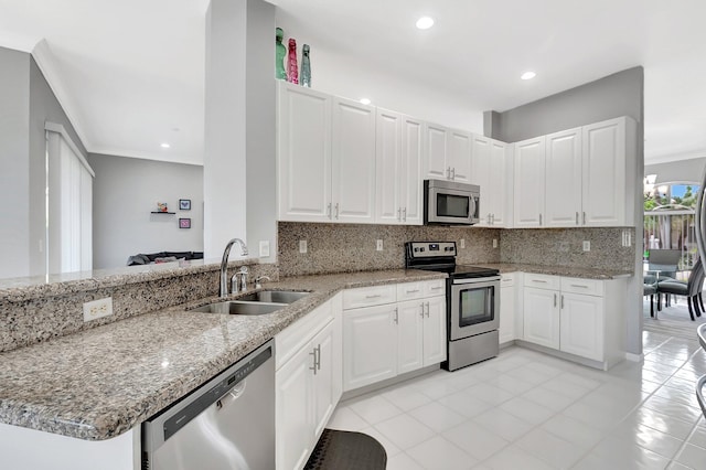 kitchen featuring stainless steel appliances, light stone counters, a sink, and decorative backsplash