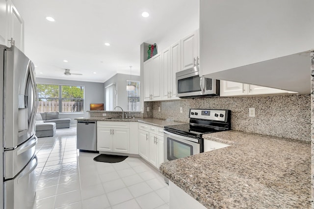 kitchen featuring tasteful backsplash, open floor plan, a peninsula, stainless steel appliances, and a sink