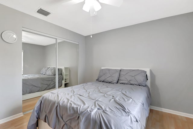 bedroom featuring a closet, visible vents, ceiling fan, wood finished floors, and baseboards