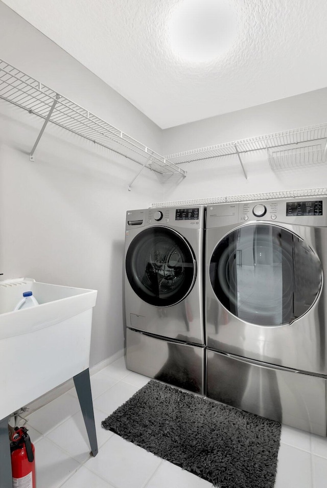 washroom featuring laundry area, baseboards, tile patterned floors, independent washer and dryer, and a textured ceiling