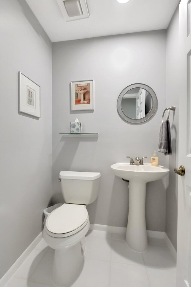 half bathroom featuring a sink, tile patterned flooring, toilet, and baseboards