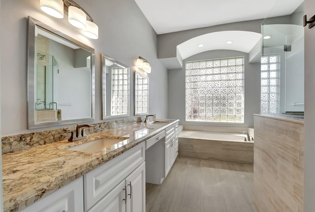 bathroom with a shower, a garden tub, a sink, and double vanity