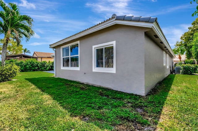 view of property exterior with a yard, central AC unit, and stucco siding