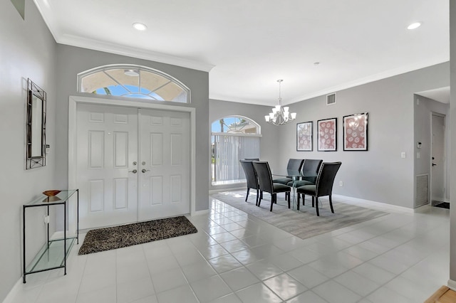 foyer entrance with light tile patterned floors, baseboards, visible vents, crown molding, and a chandelier