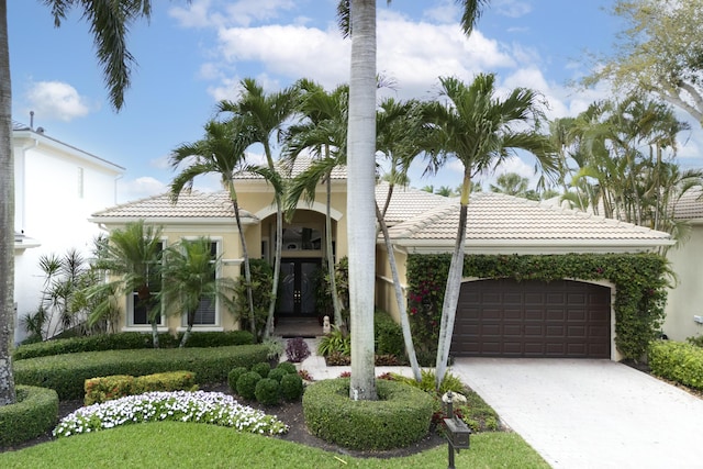 mediterranean / spanish house featuring a garage, a tile roof, and concrete driveway