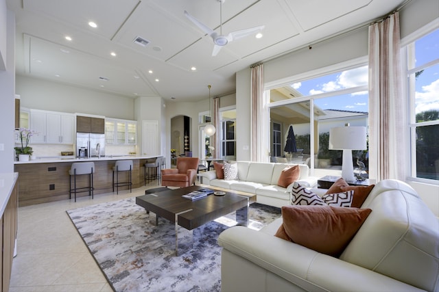 living area featuring light tile patterned floors, visible vents, arched walkways, ceiling fan, and recessed lighting