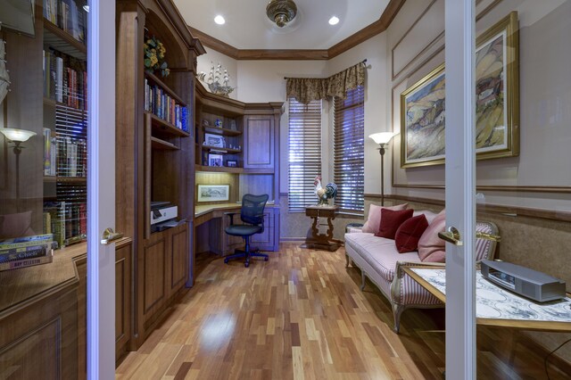 office space with light wood finished floors, built in desk, and crown molding