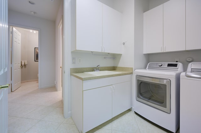 clothes washing area with washer and dryer, cabinet space, a sink, and light tile patterned floors