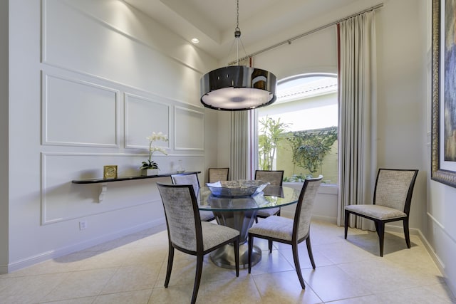 dining room featuring light tile patterned floors, a towering ceiling, and baseboards