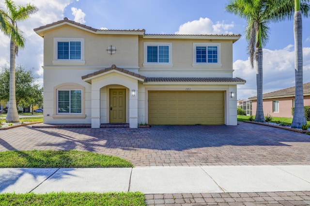 view of front of home with an attached garage, a tile roof, decorative driveway, and stucco siding