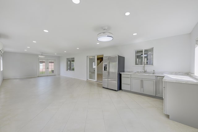 kitchen with recessed lighting, a sink, light countertops, french doors, and stainless steel fridge