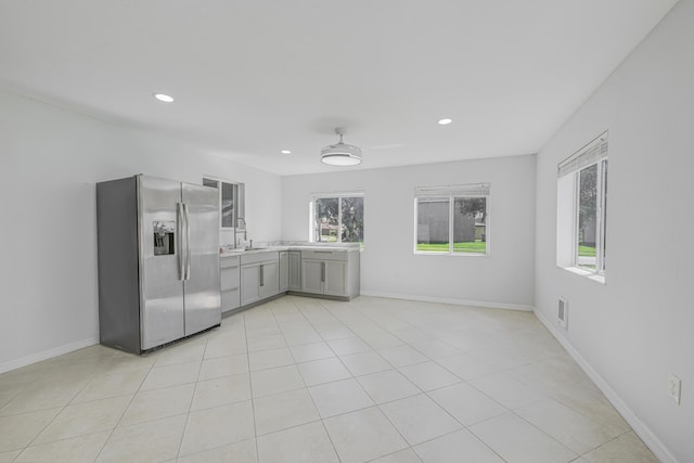 kitchen with gray cabinetry, a sink, light countertops, plenty of natural light, and stainless steel fridge