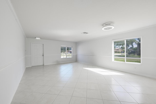 empty room with visible vents, crown molding, baseboards, and light tile patterned floors