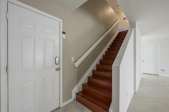 staircase with visible vents, baseboards, and tile patterned floors