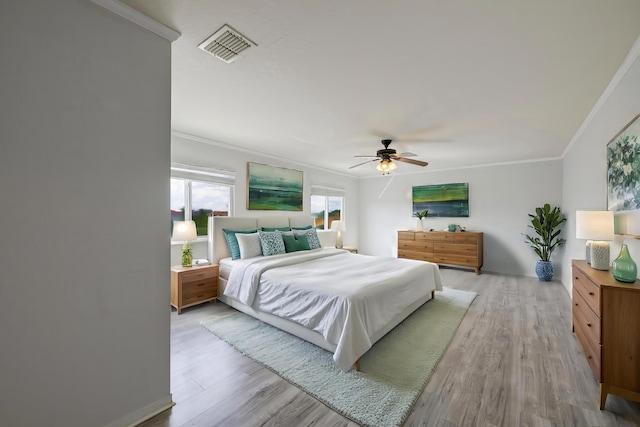 bedroom with light wood-style floors, visible vents, crown molding, and ceiling fan