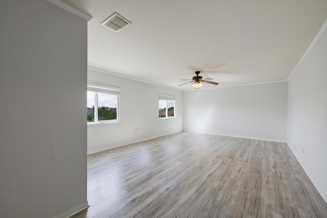 empty room featuring visible vents, crown molding, light wood-style flooring, and ceiling fan