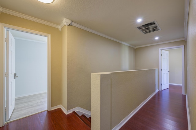 hall with baseboards, visible vents, wood finished floors, crown molding, and an upstairs landing