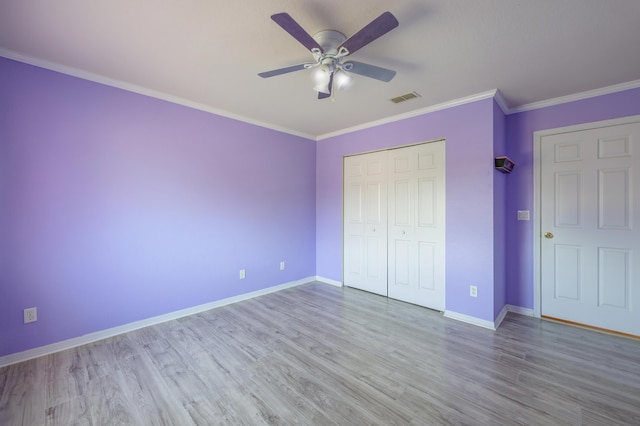 unfurnished bedroom with visible vents, crown molding, baseboards, and wood finished floors