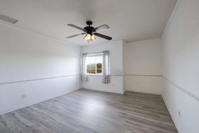 spare room featuring ceiling fan, wood finished floors, visible vents, and crown molding