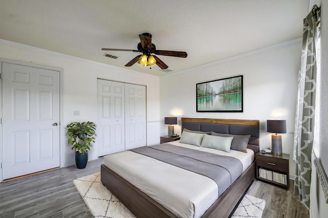 bedroom featuring ornamental molding, a closet, visible vents, and wood finished floors