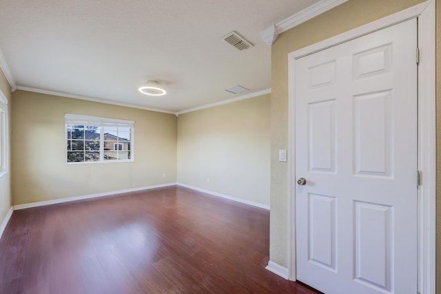 unfurnished room featuring dark wood-type flooring, visible vents, crown molding, and baseboards