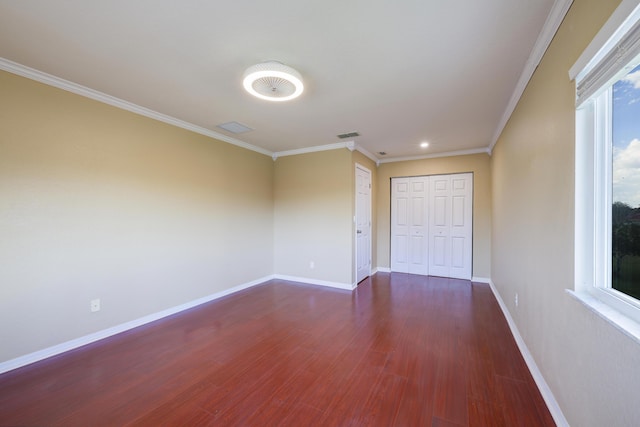 spare room featuring dark wood-style floors, visible vents, ornamental molding, and baseboards