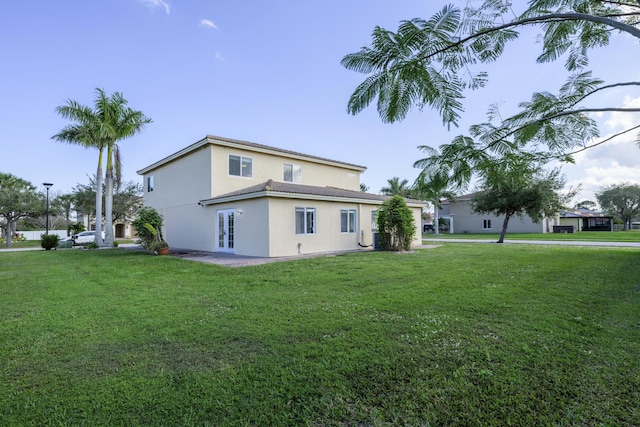 back of property featuring french doors, a yard, and stucco siding