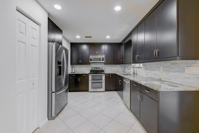 kitchen featuring stainless steel appliances, a sink, visible vents, decorative backsplash, and light stone countertops