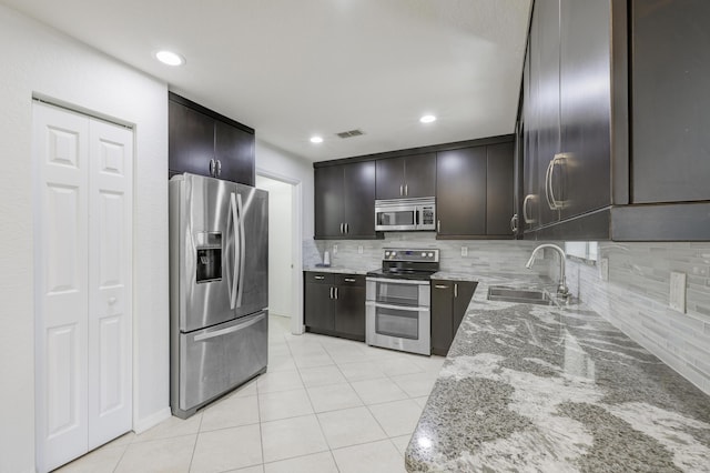 kitchen featuring light stone counters, visible vents, backsplash, appliances with stainless steel finishes, and a sink