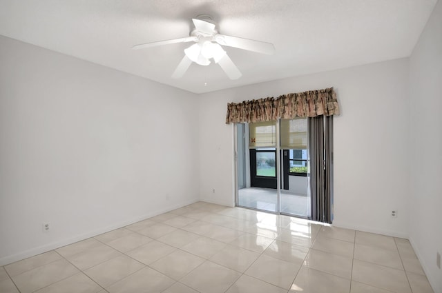 empty room with light tile patterned floors, ceiling fan, and baseboards