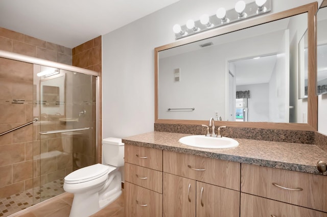 full bathroom featuring toilet, visible vents, vanity, a shower stall, and tile patterned floors