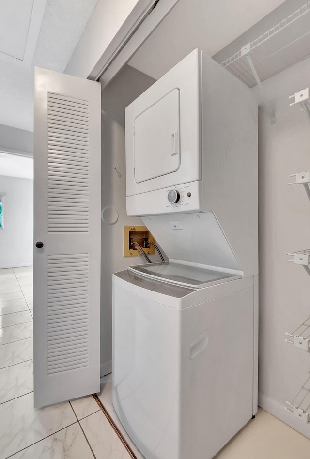 clothes washing area featuring laundry area, marble finish floor, and stacked washer / drying machine