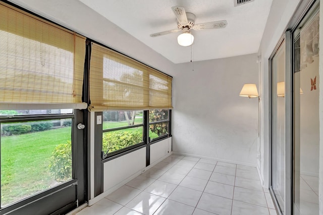 interior space featuring baseboards, visible vents, a ceiling fan, and light tile patterned flooring