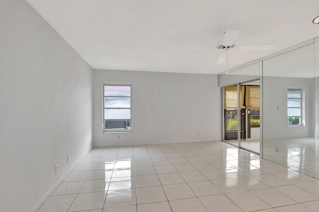 spare room with a ceiling fan, a healthy amount of sunlight, and light tile patterned floors