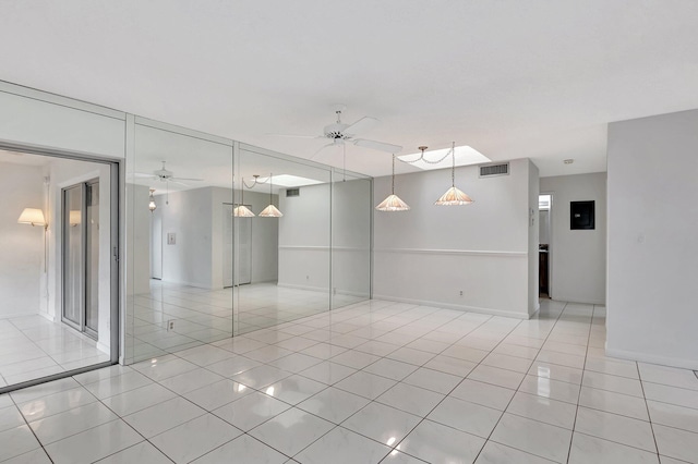 empty room with a ceiling fan, light tile patterned flooring, visible vents, and baseboards