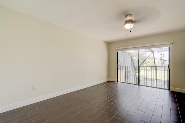 spare room with dark wood-style flooring, ceiling fan, and baseboards