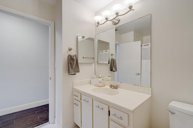 bathroom with vanity, wood finished floors, toilet, and baseboards