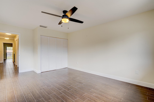 unfurnished bedroom with dark wood-style floors, baseboards, visible vents, and a closet