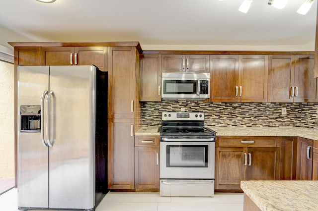 kitchen with stainless steel appliances, light stone countertops, light tile patterned floors, and tasteful backsplash