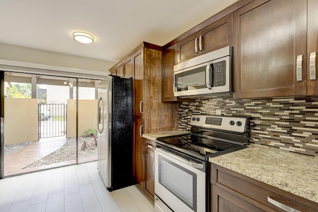 kitchen with light stone counters, stainless steel appliances, and decorative backsplash