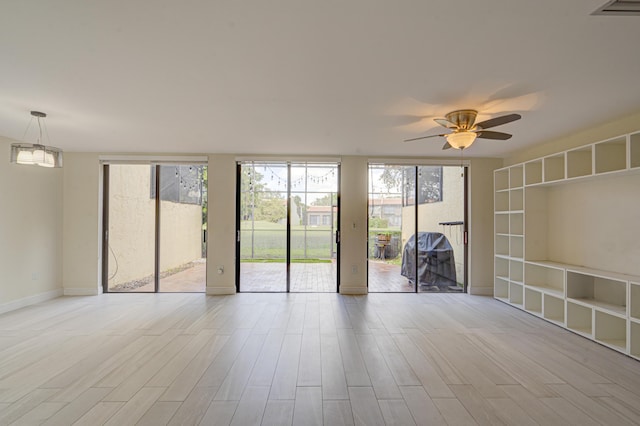 spare room with ceiling fan with notable chandelier, floor to ceiling windows, baseboards, and wood finished floors