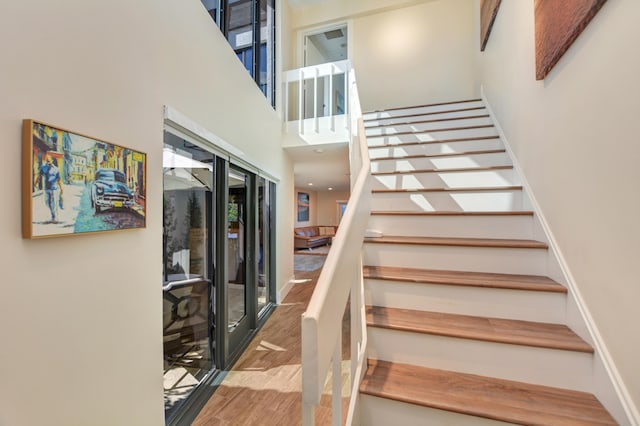 staircase with a high ceiling and wood finished floors