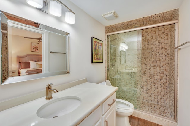 ensuite bathroom with toilet, a shower stall, visible vents, and vanity