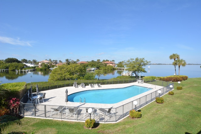 pool featuring a patio, a yard, a water view, and fence