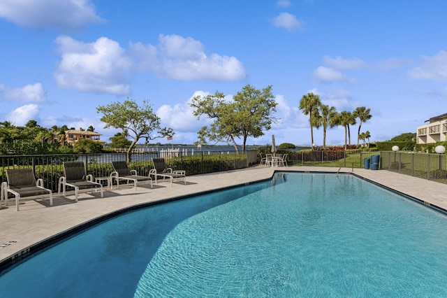 community pool with a patio area and fence